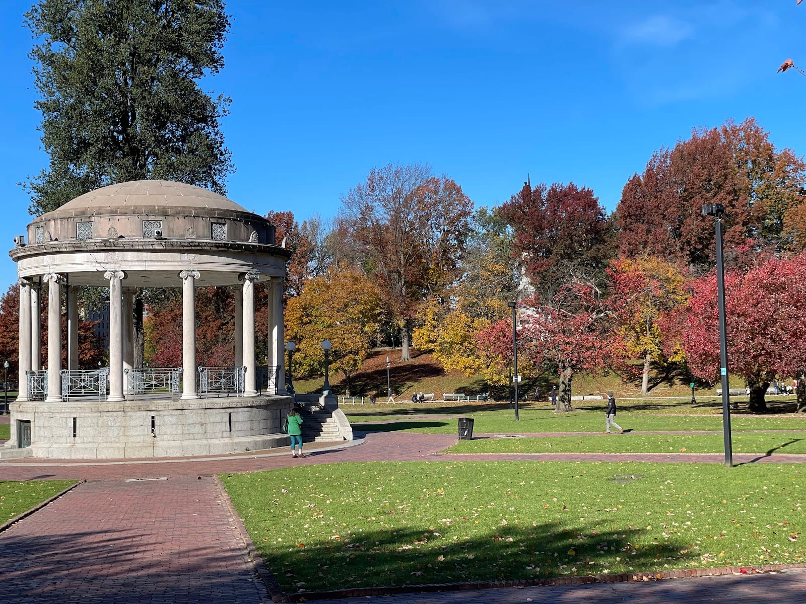 Autumn trees in vibrant red and orange along the walking paths of Boston Common.