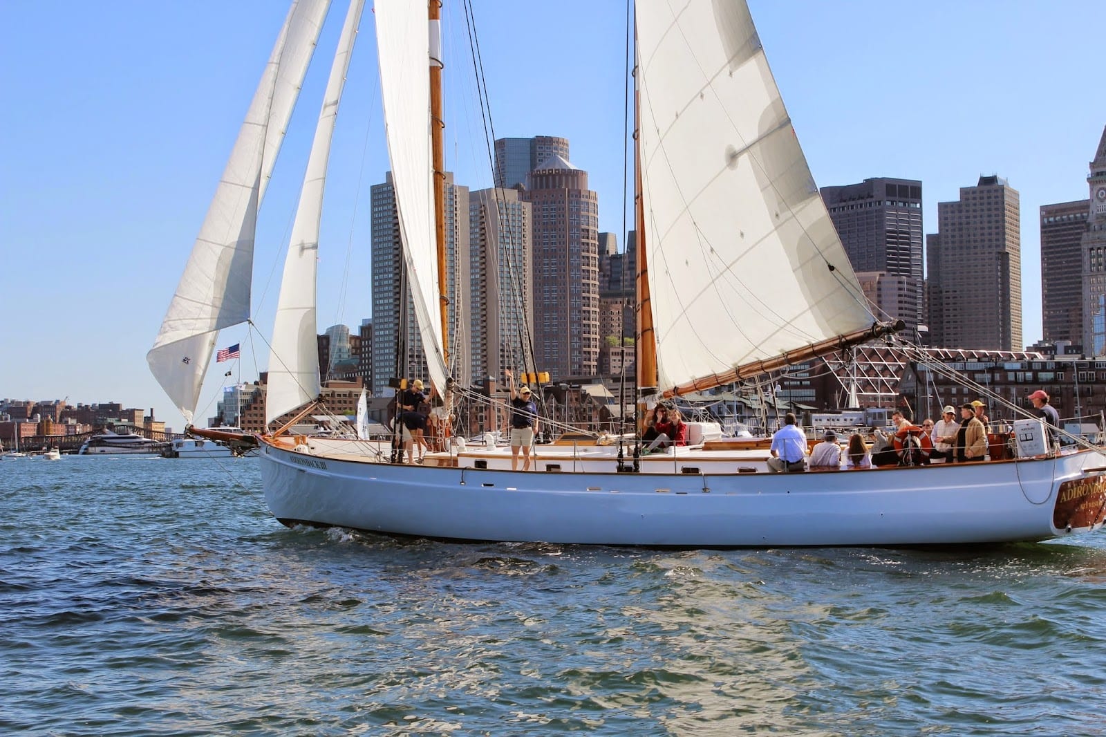 Boston skyline and harbor on a bright summer day with sailboats on the water.