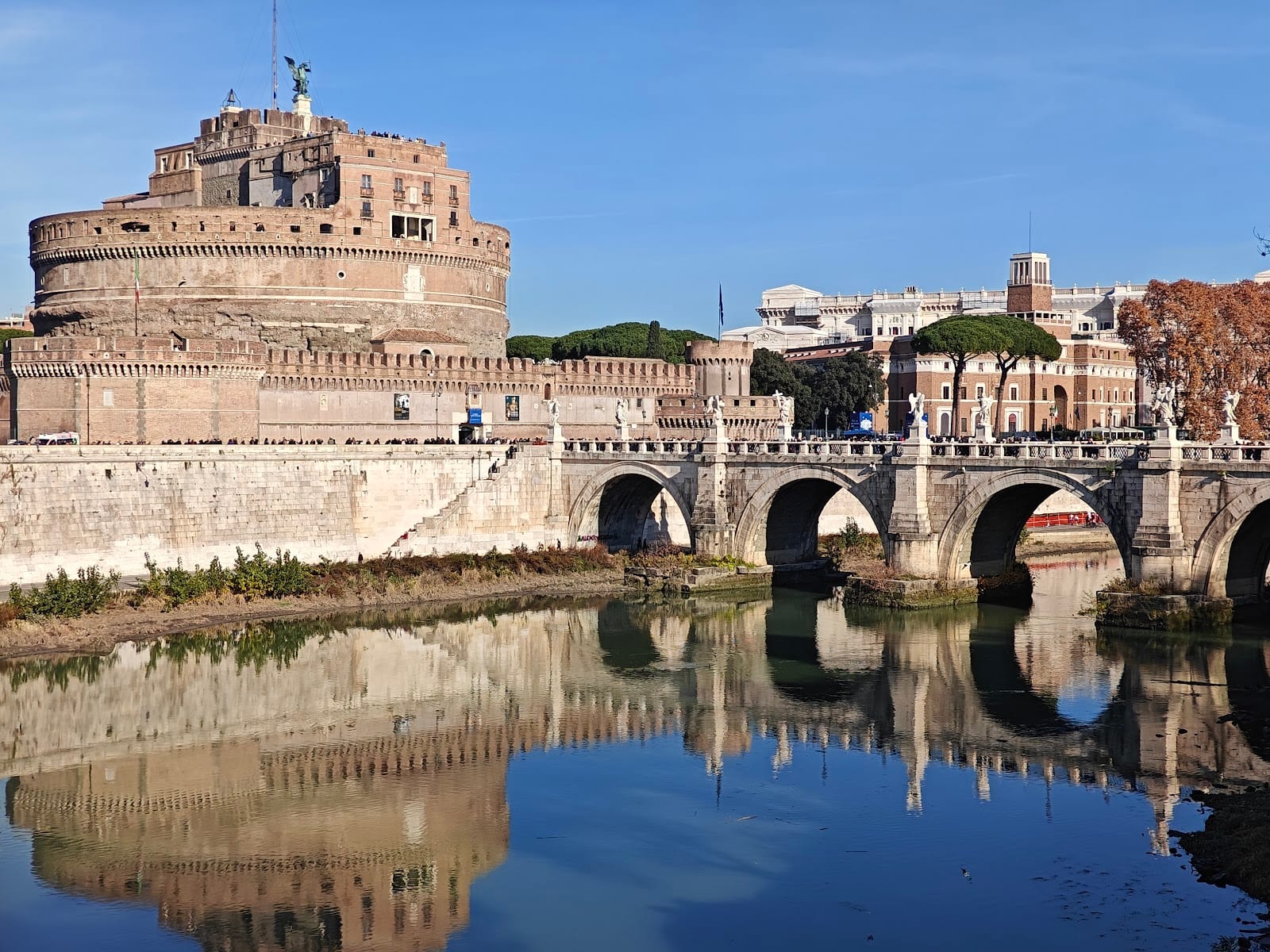 Castel Sant'Angelo and its bridge reflected in the Tiber at blue hour on a summer evening.