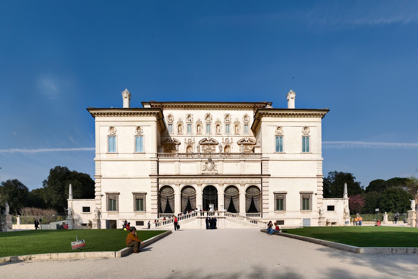 A panoramic view over Rome's rooftops to St Peter's dome, framed by trees turning autumn gold in Villa Borghese.