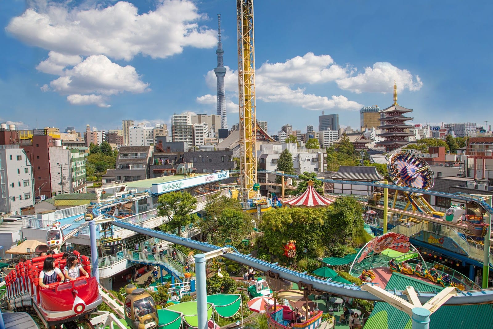 The compact rides of Hanayashiki with Senso-ji's pagoda and Skytree behind.