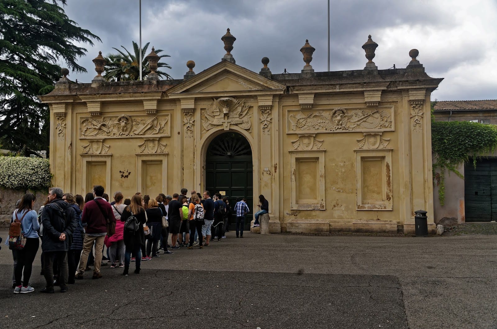 Visitors queueing at the green priory gate on Piazza dei Cavalieri di Malta.