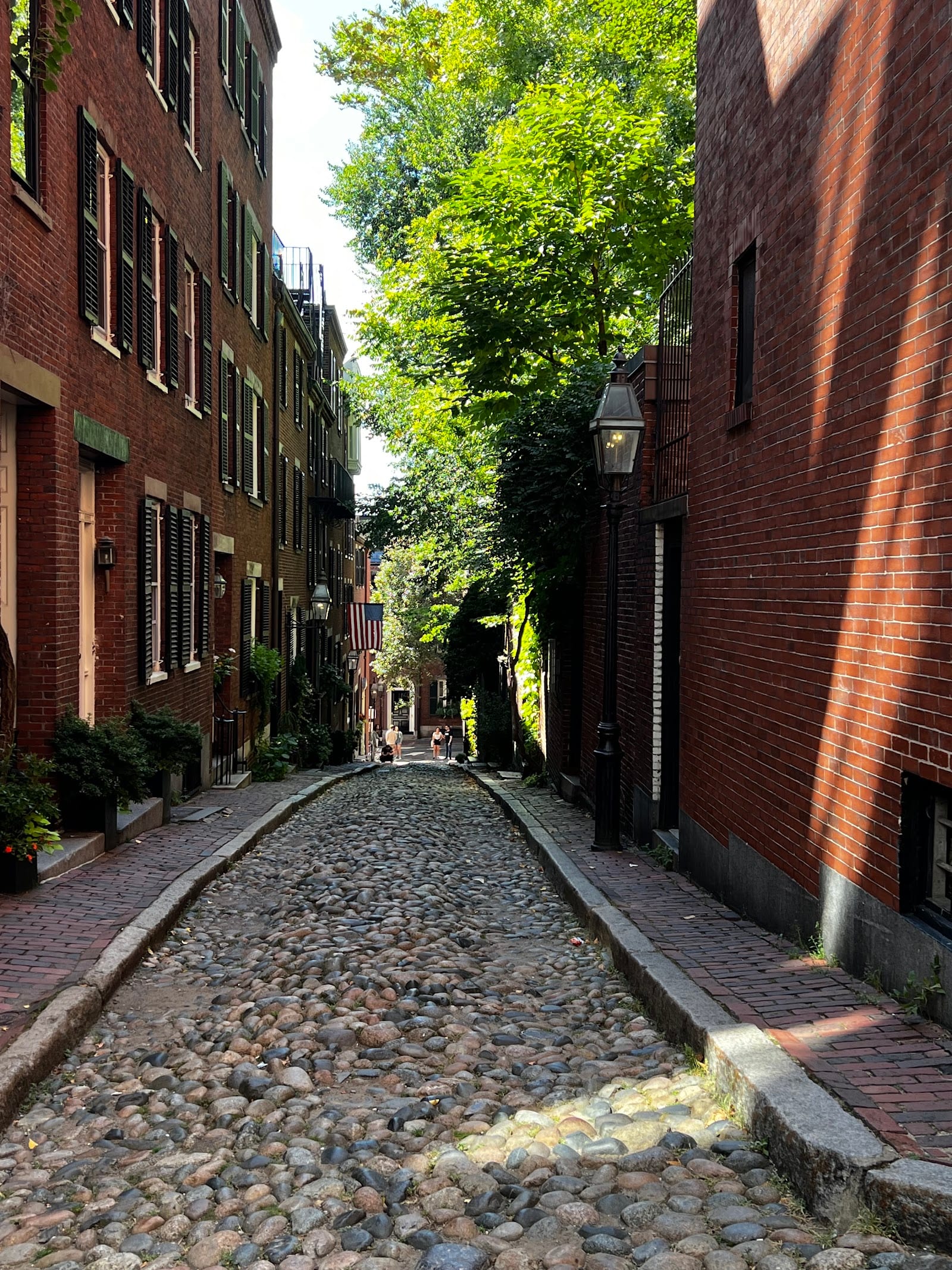 Acorn Street on Beacon Hill, cobblestones and brick row houses with American flags