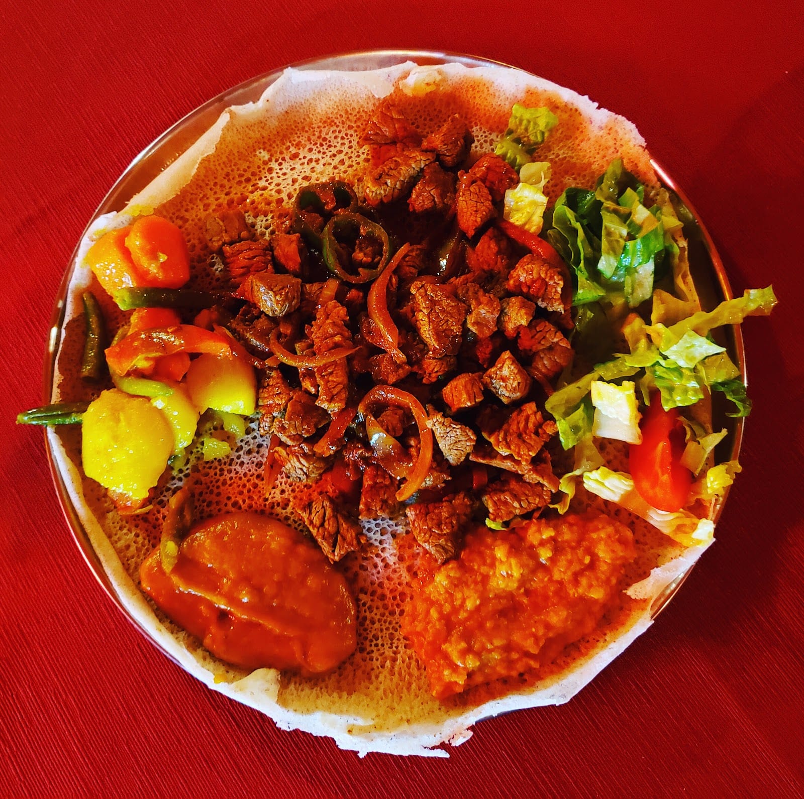 A colorful Eritrean zighinì platter served on injera at Africa Restaurant in Rome.