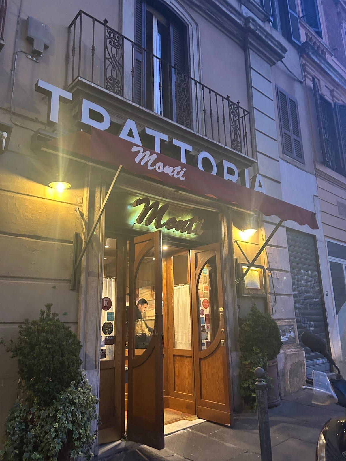 The lit storefront and sign of Trattoria Monti near Piazza Vittorio in Rome.