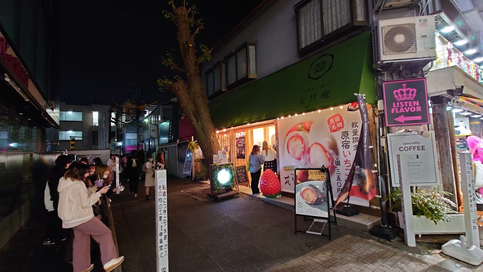 Lit-up food and fashion shopfronts on Takeshita Street in the evening.