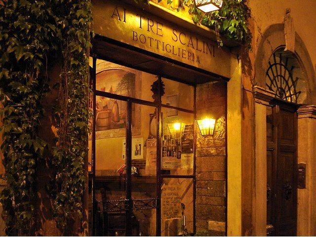The ivy-framed entrance of the Ai Tre Scalini wine bar in Monti at night.