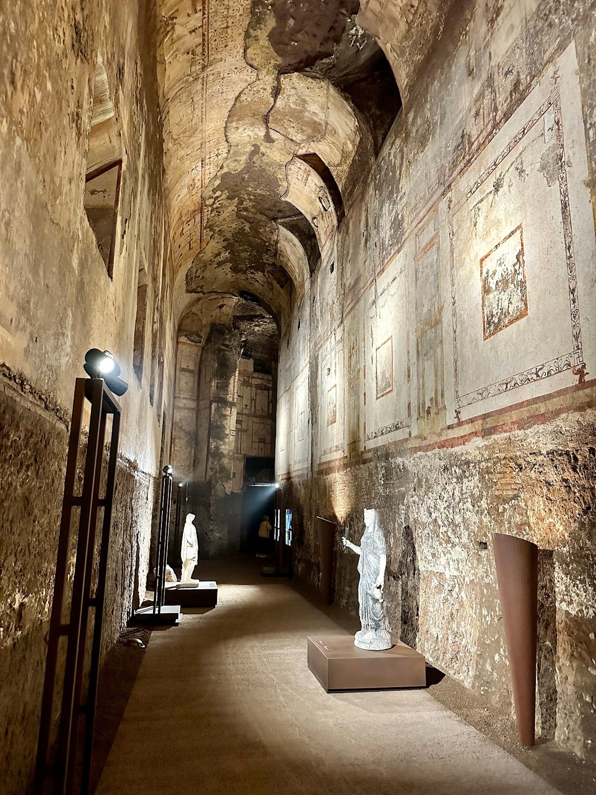 A lit corridor of the Domus Aurea with a statue in the distance.