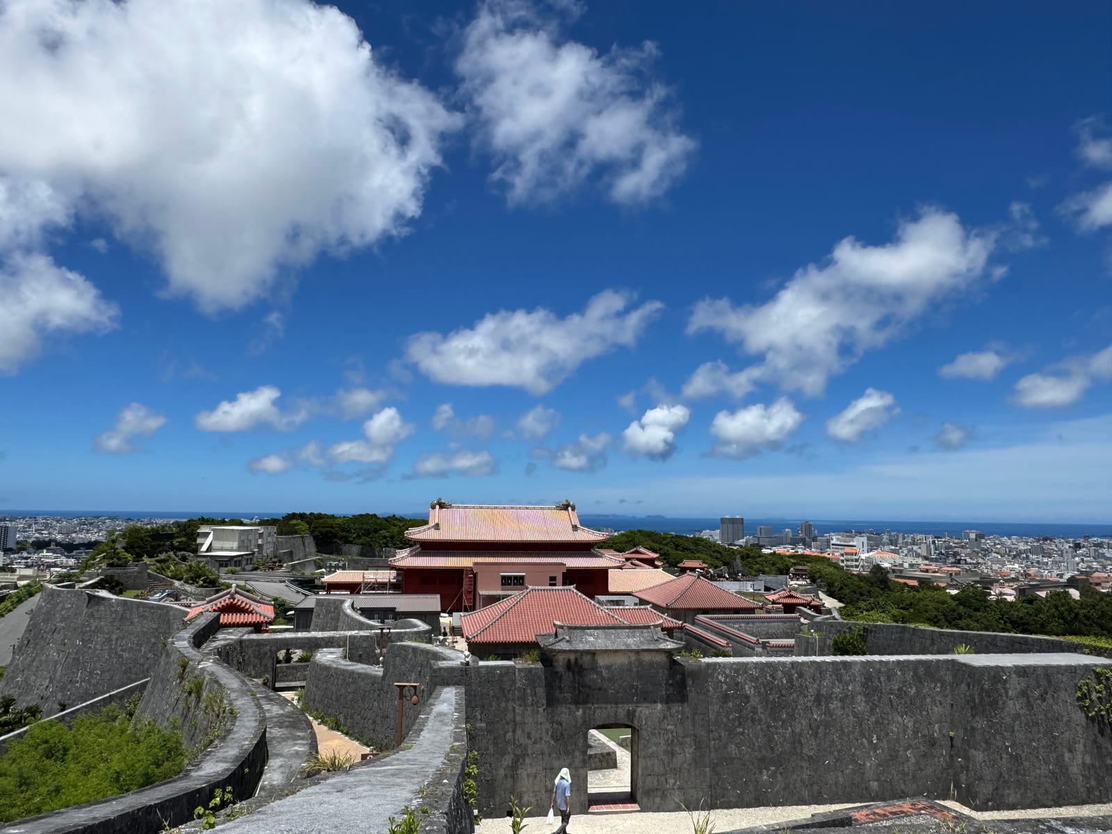 Shuri Castle's red-tiled buildings and stone walls overlook Naha and the surrounding coastline.