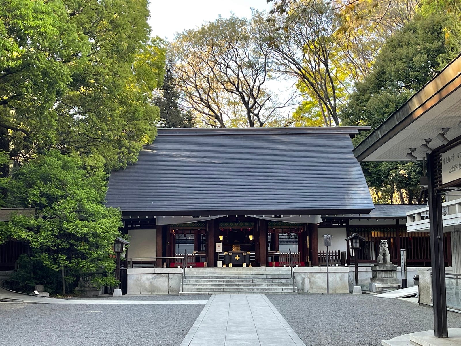 The wooden main hall of Nogi Shrine among green trees.