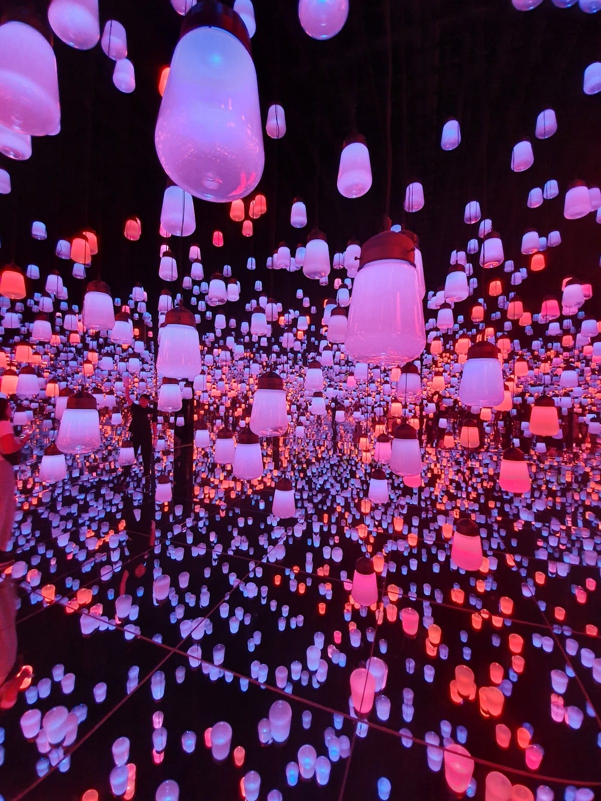 Glowing lamps fill a mirrored room at teamLab Borderless.