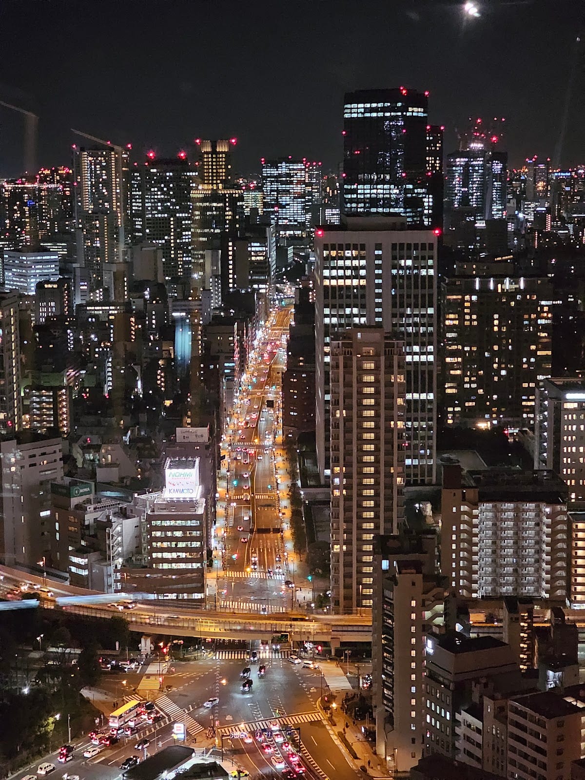 Tokyo Tower at the end of a lit Minato street after dark.