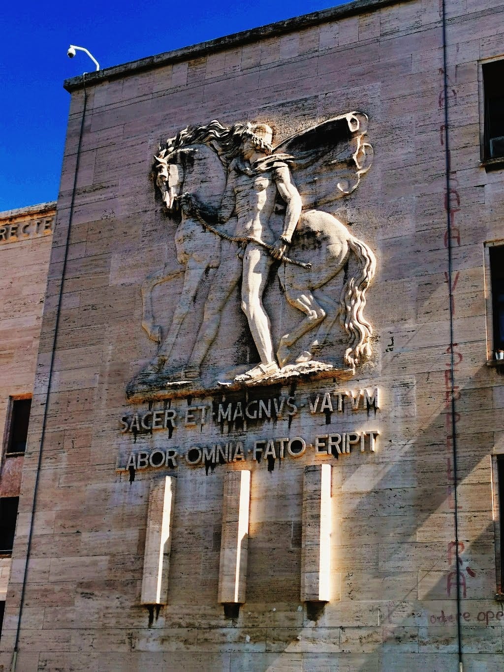 A rationalist relief with a Latin inscription on a Sapienza campus building.