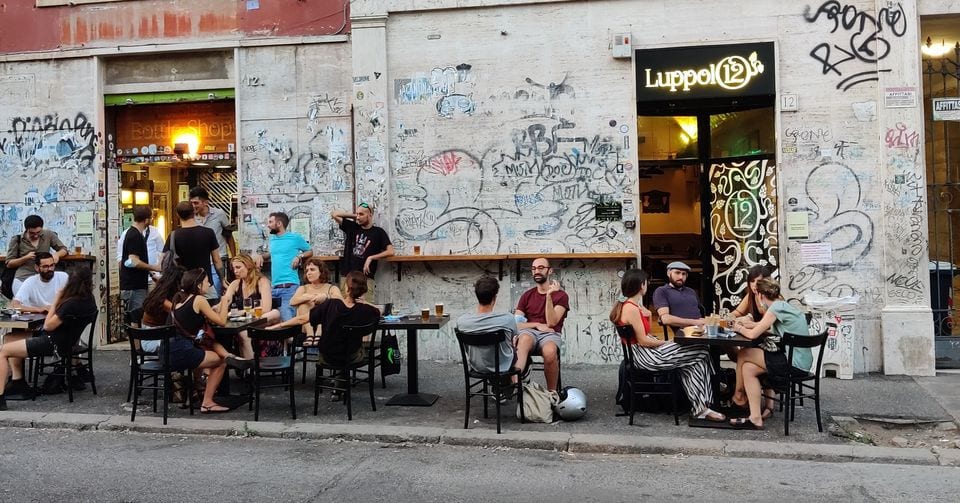 The graffiti-covered exterior and outdoor tables of the Luppolo12 craft-beer bar.