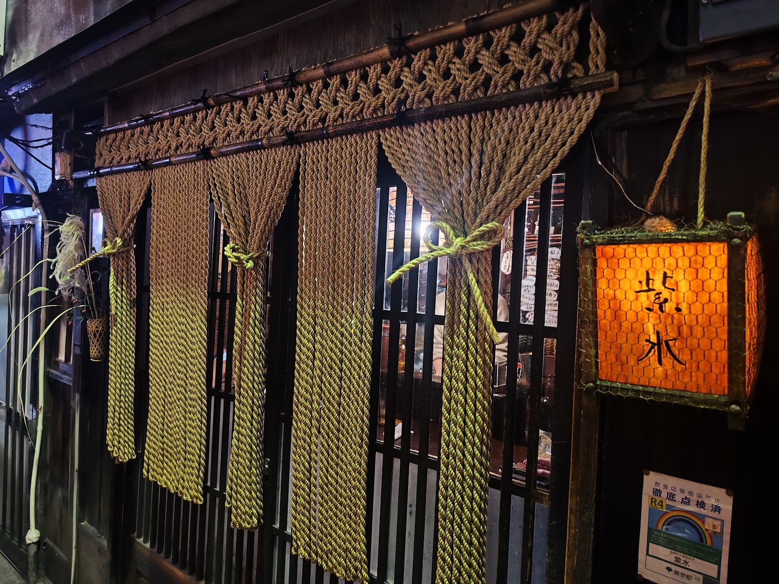 The lantern-lit wooden facade of a Nonbei Yokocho bar.