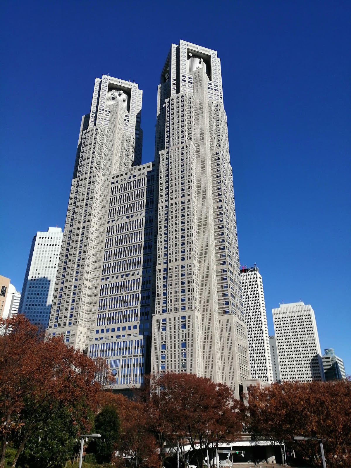 The twin towers of the Tokyo Metropolitan Government Building against a blue sky.