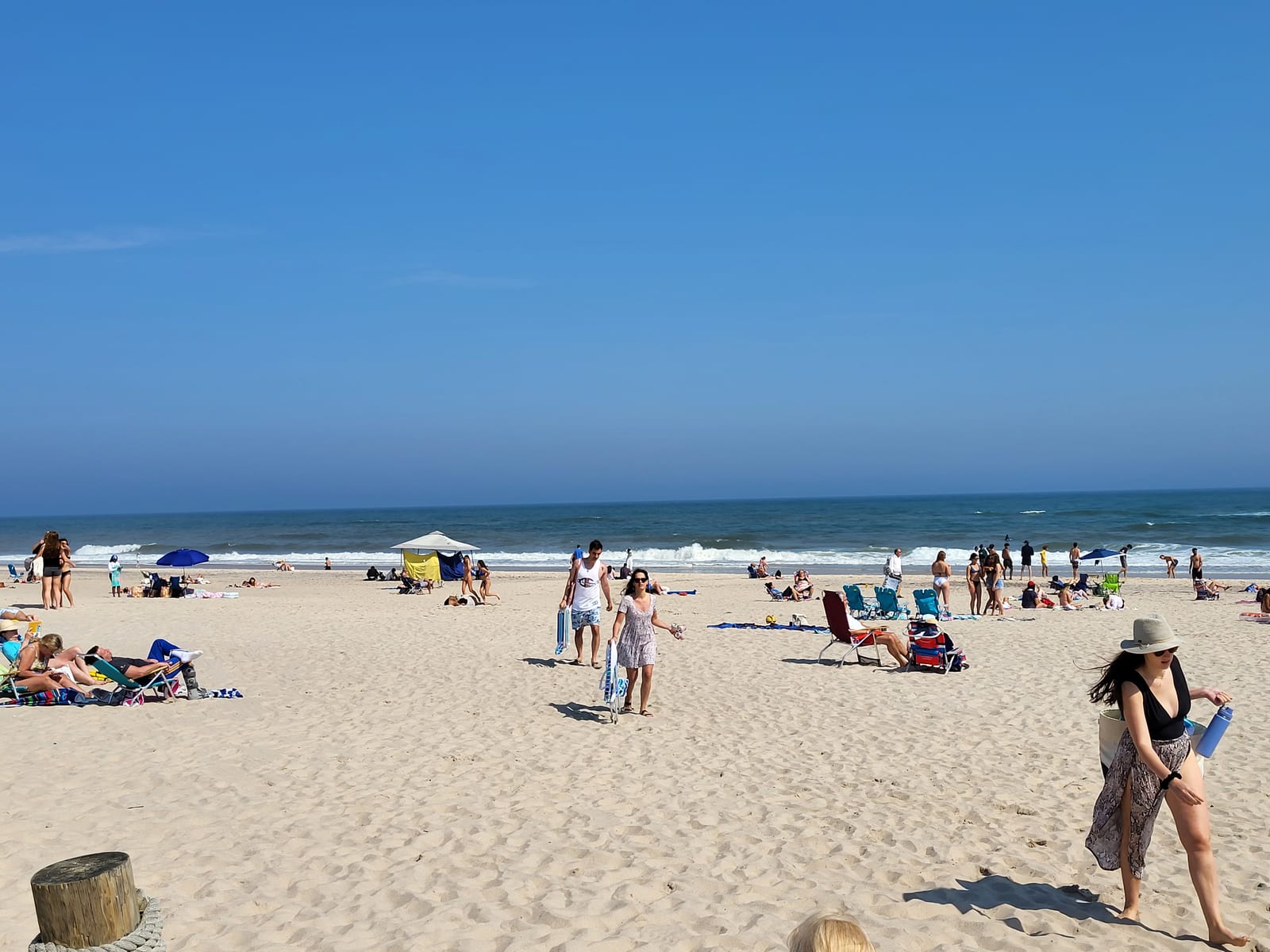 Coopers Beach in Southampton with a sandy shore, ocean waves, beachgoers, and umbrellas.