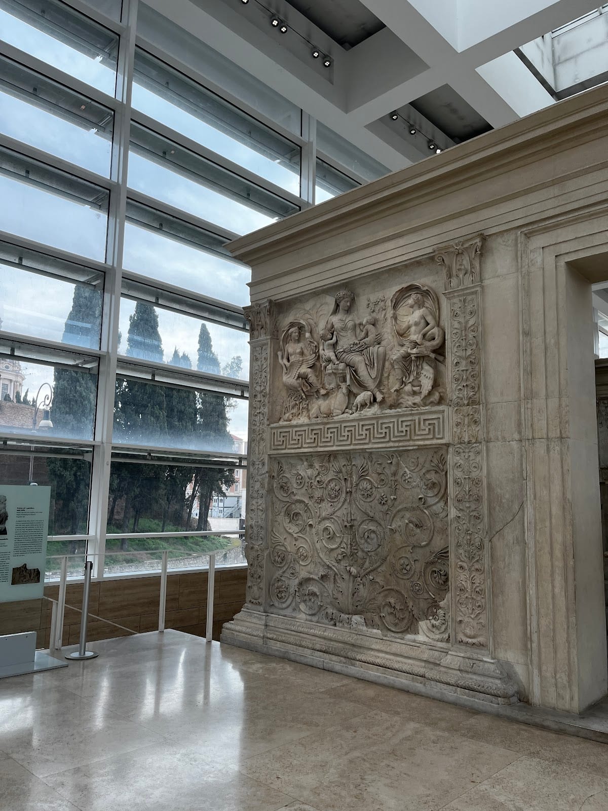 The carved marble altar against the glass wall and cypresses outside.