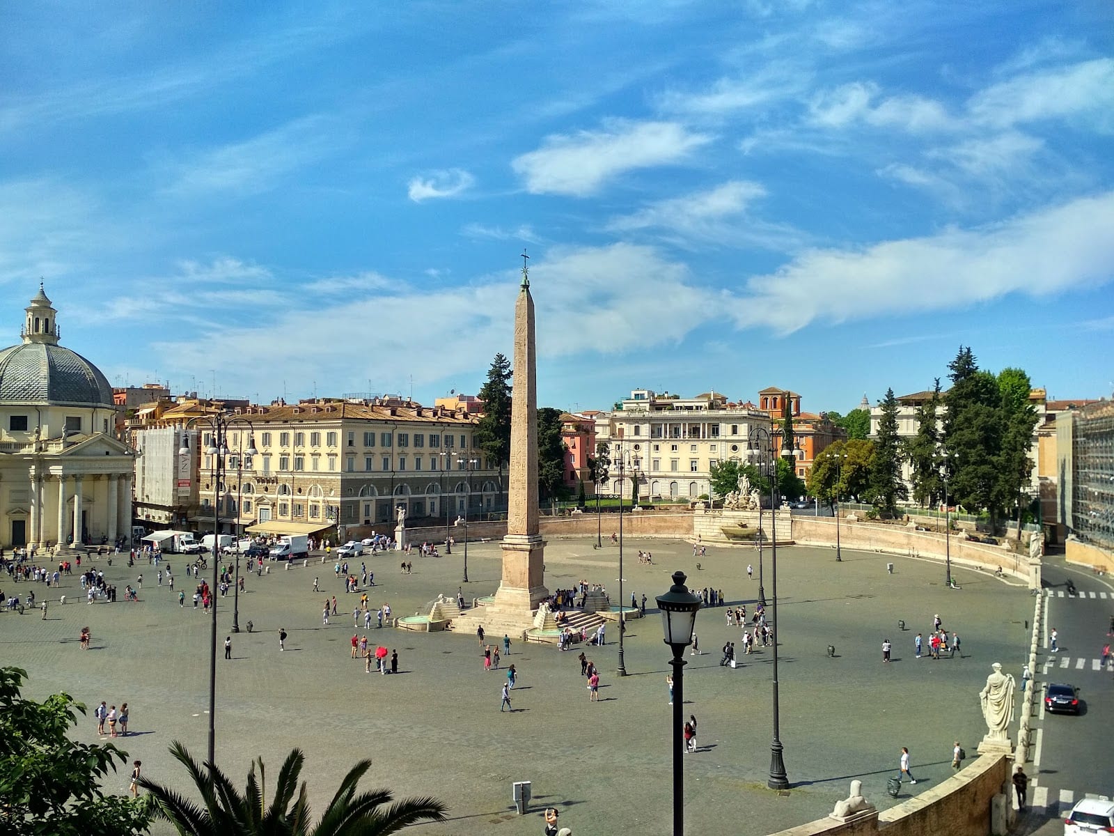 A wide daytime view across the oval of Piazza del Popolo.