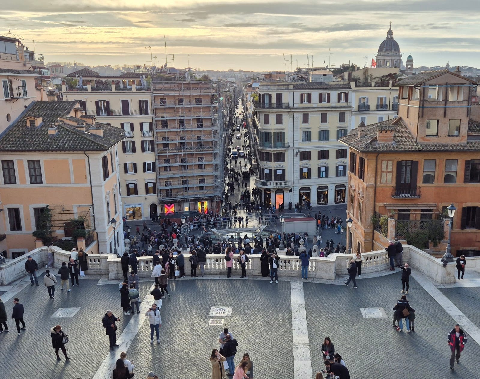 The view down Via dei Condotti toward St Peter's dome, lined with shops.
