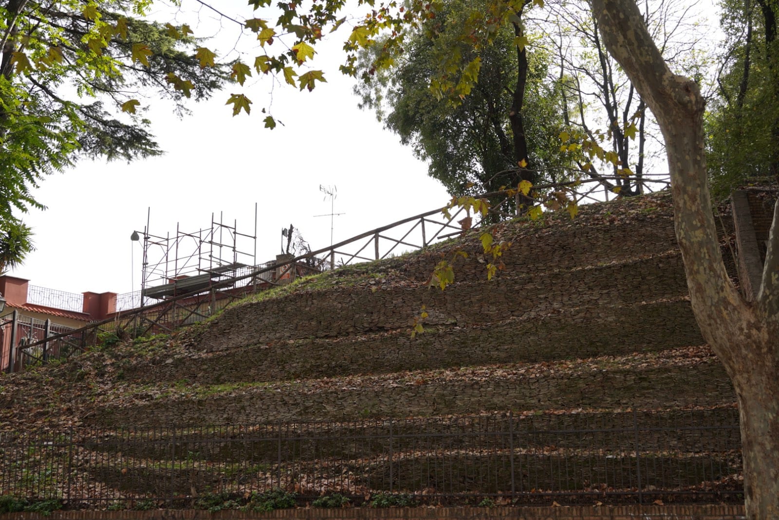 The terraced, grass-covered slope of Monte Testaccio behind a fence.