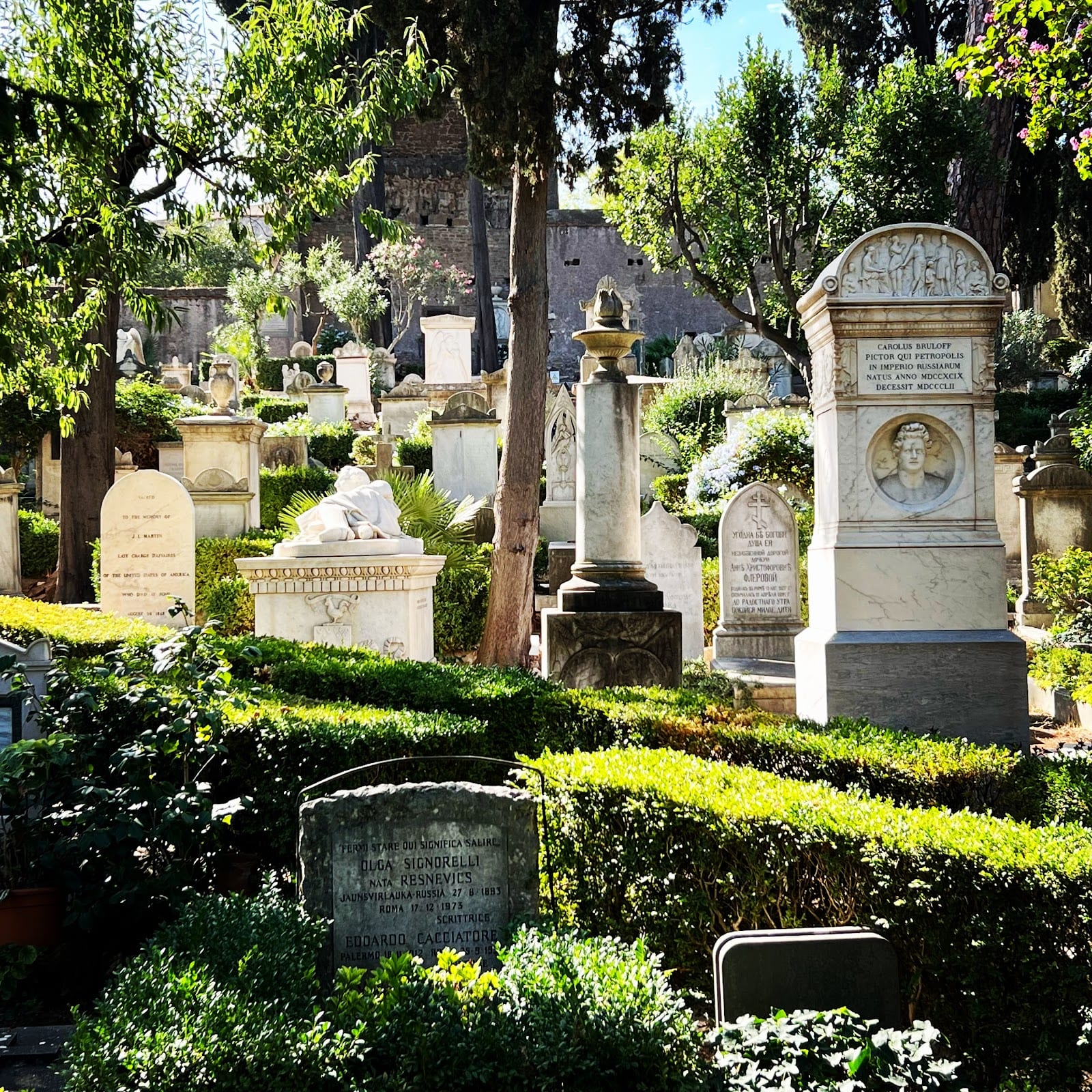 Rows of old gravestones among greenery in the Non-Catholic Cemetery in Rome.