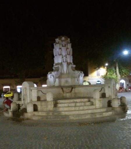 The amphora fountain of Piazza Testaccio lit up at night.