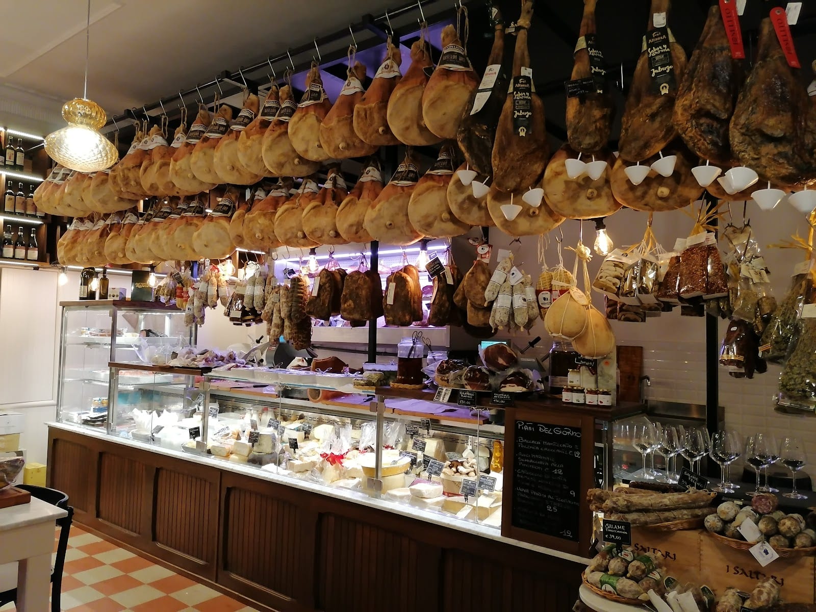 Cured hams hanging over the counter inside Salumeria Volpetti.