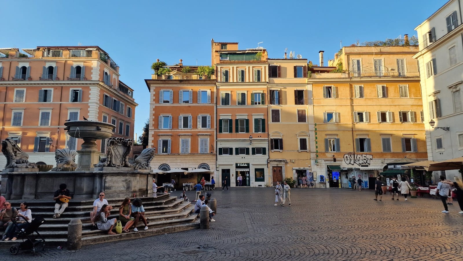 The fountain and warm-toned buildings of Piazza di Santa Maria in Trastevere.