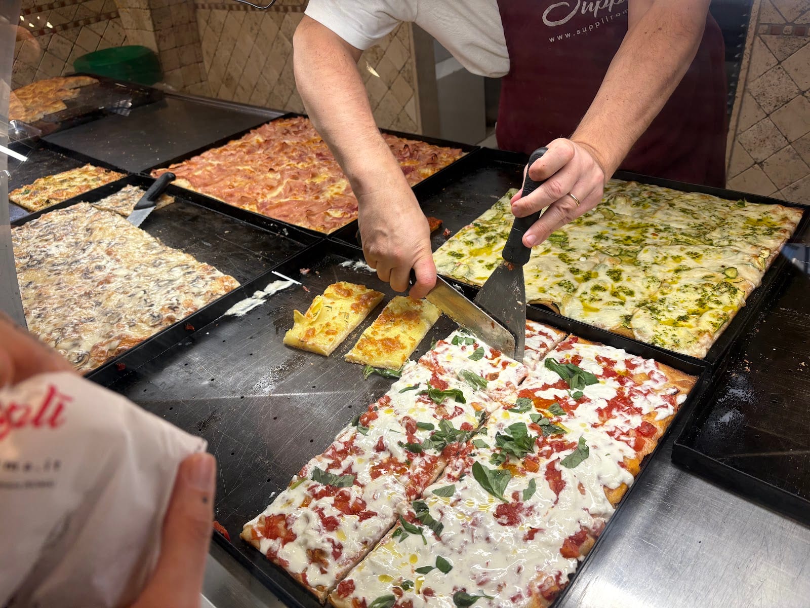 Pizza al taglio being cut at Supplì Roma.