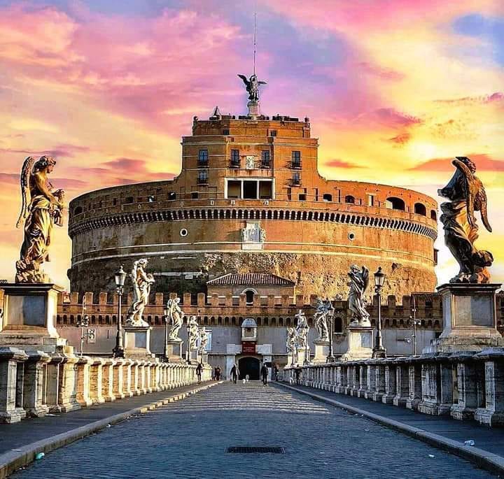 Castel Sant'Angelo at sunset with the angel statues of the Ponte Sant'Angelo in the foreground.