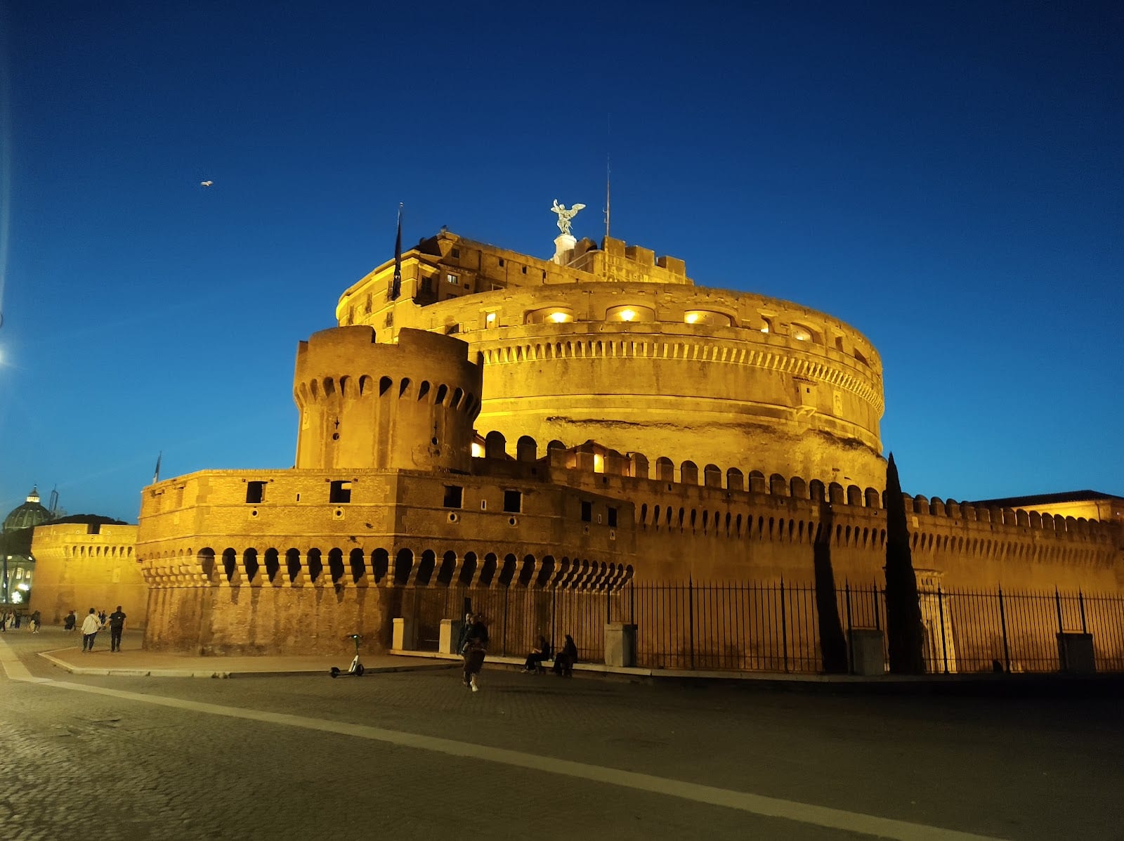 Castel Sant'Angelo at sunset with the angel statues of the Ponte Sant'Angelo in the foreground.
