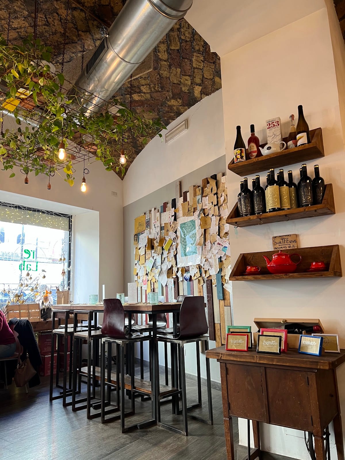 The bright dining room of Fa-Bio (reLab) with wine shelves and a postcard wall.