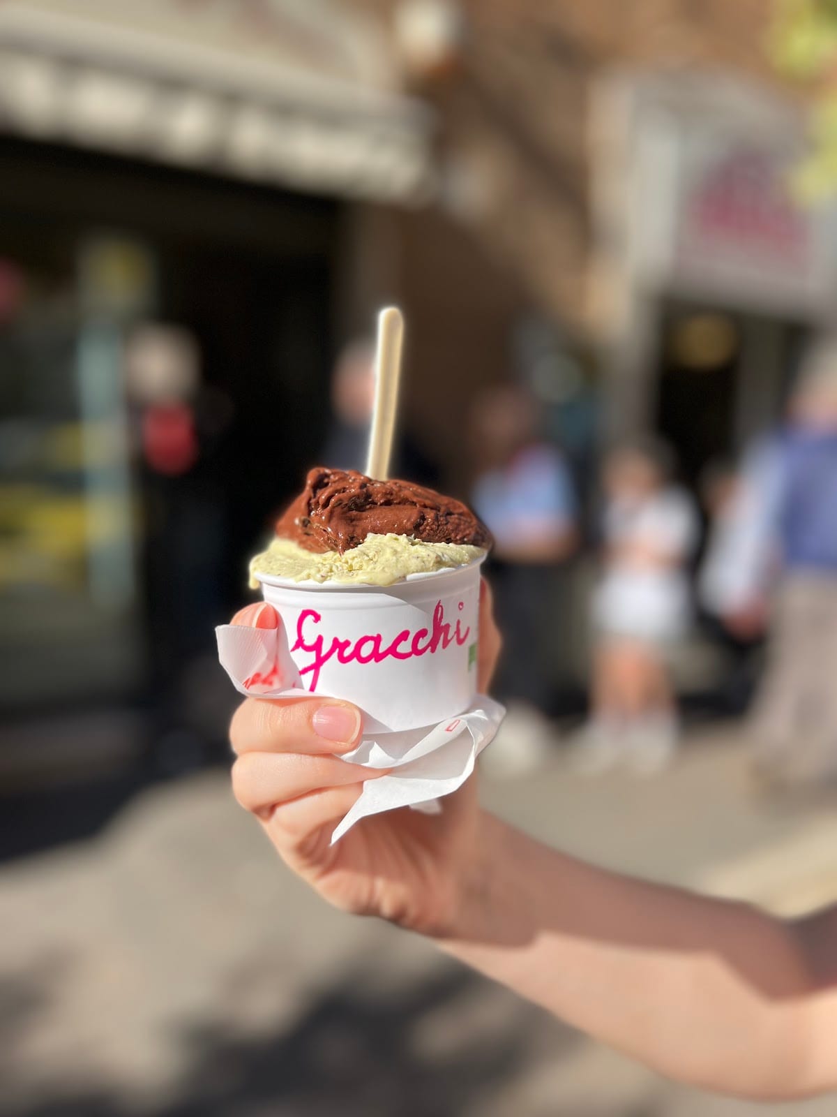 A cup of gelato in a branded Gracchi napkin held on Via dei Gracchi in Prati.