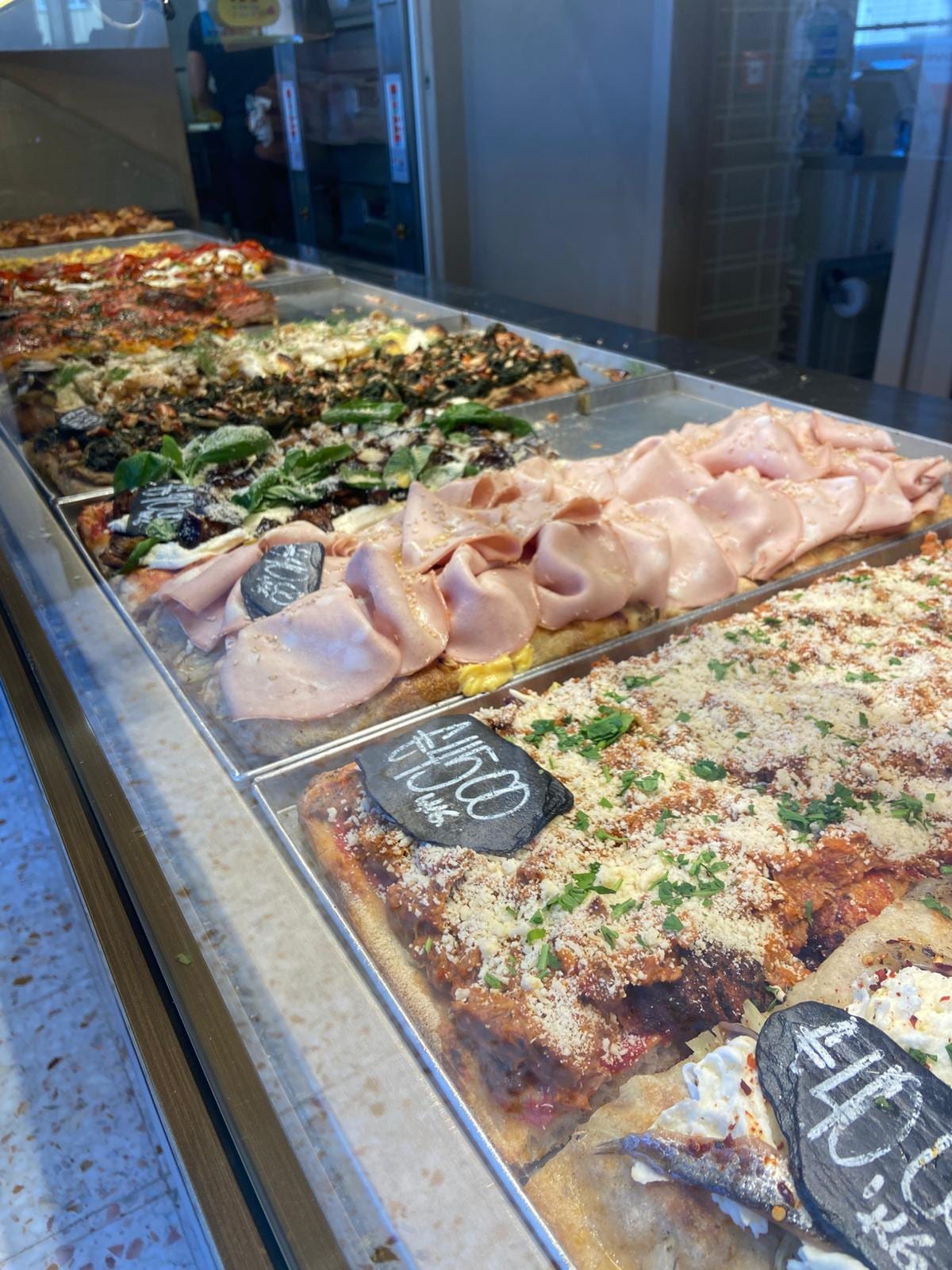 A mortadella-topped pizza al taglio in the case at Pizzarium Bonci.