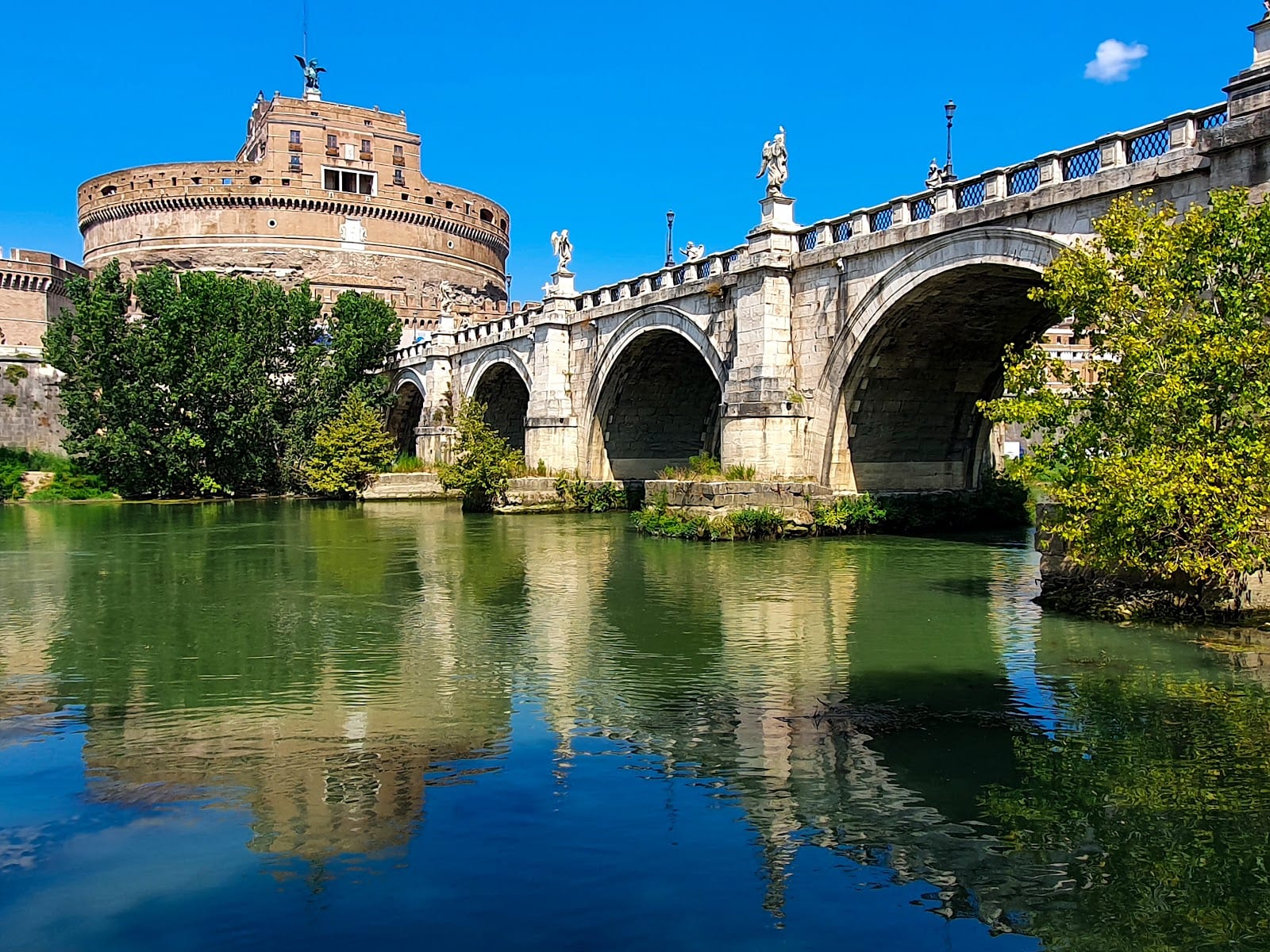 The Ponte Sant'Angelo and Castel Sant'Angelo reflected in the green Tiber.