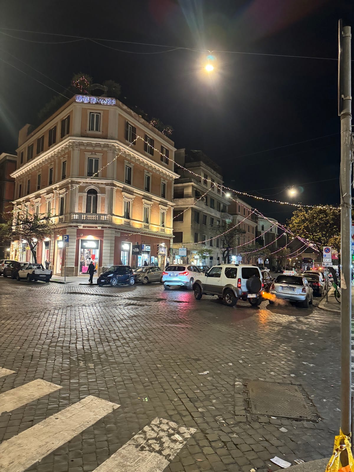 A lively corner of Via Cola di Rienzo in the evening, shops still open.