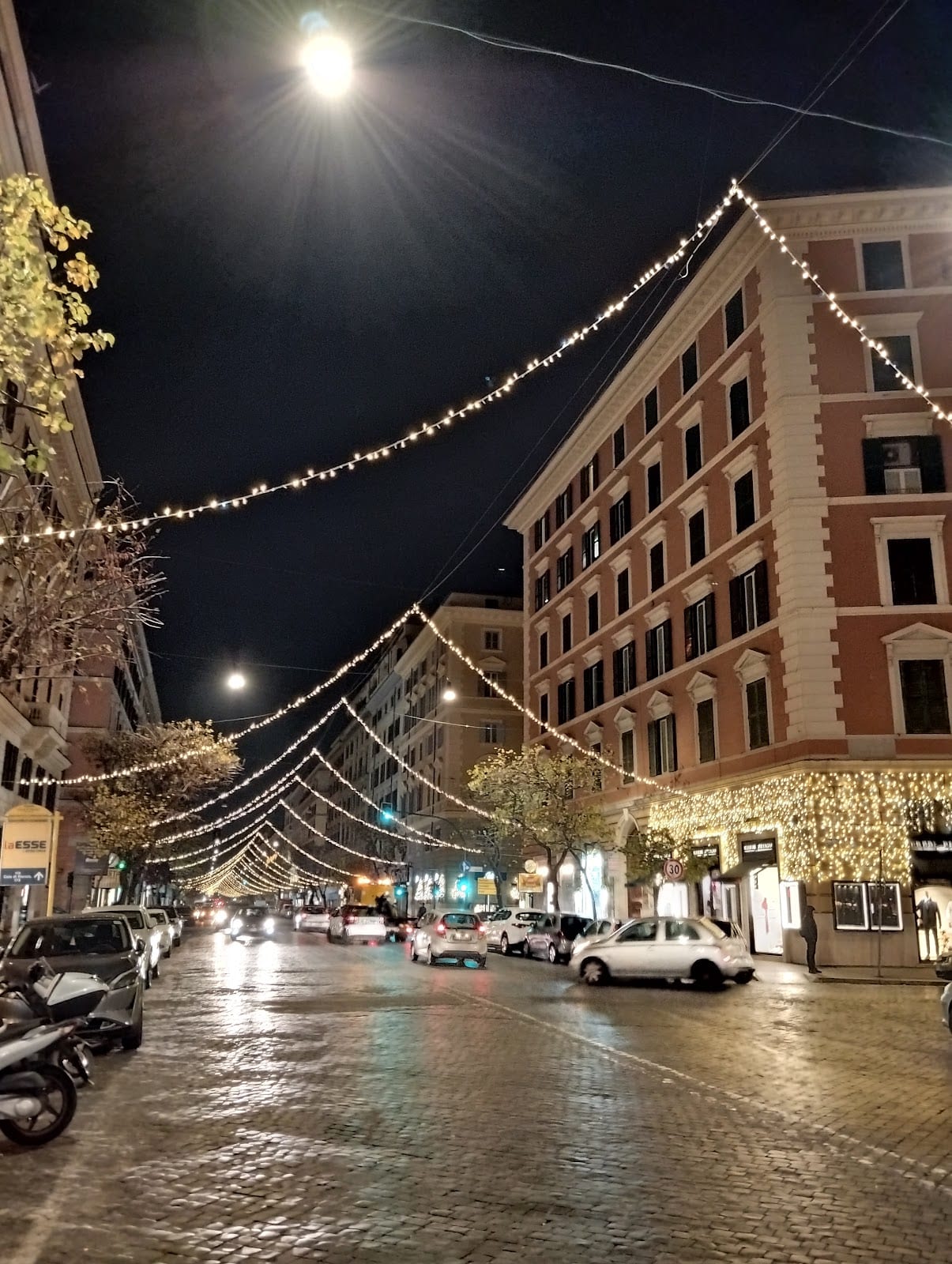 Via Cola di Rienzo strung with festoon lights at night.
