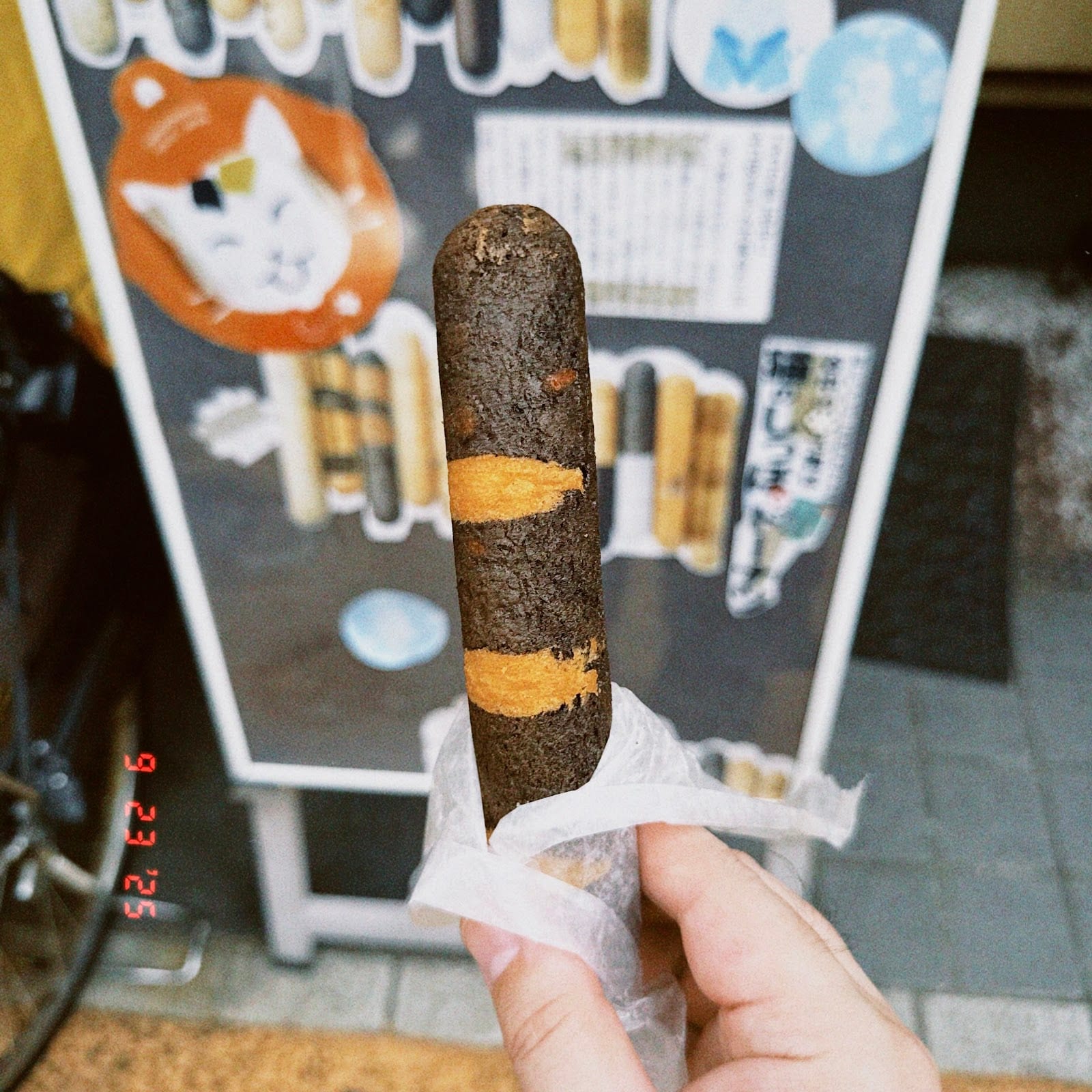 A cat-tail doughnut held up outside Yanaka Shippoya.