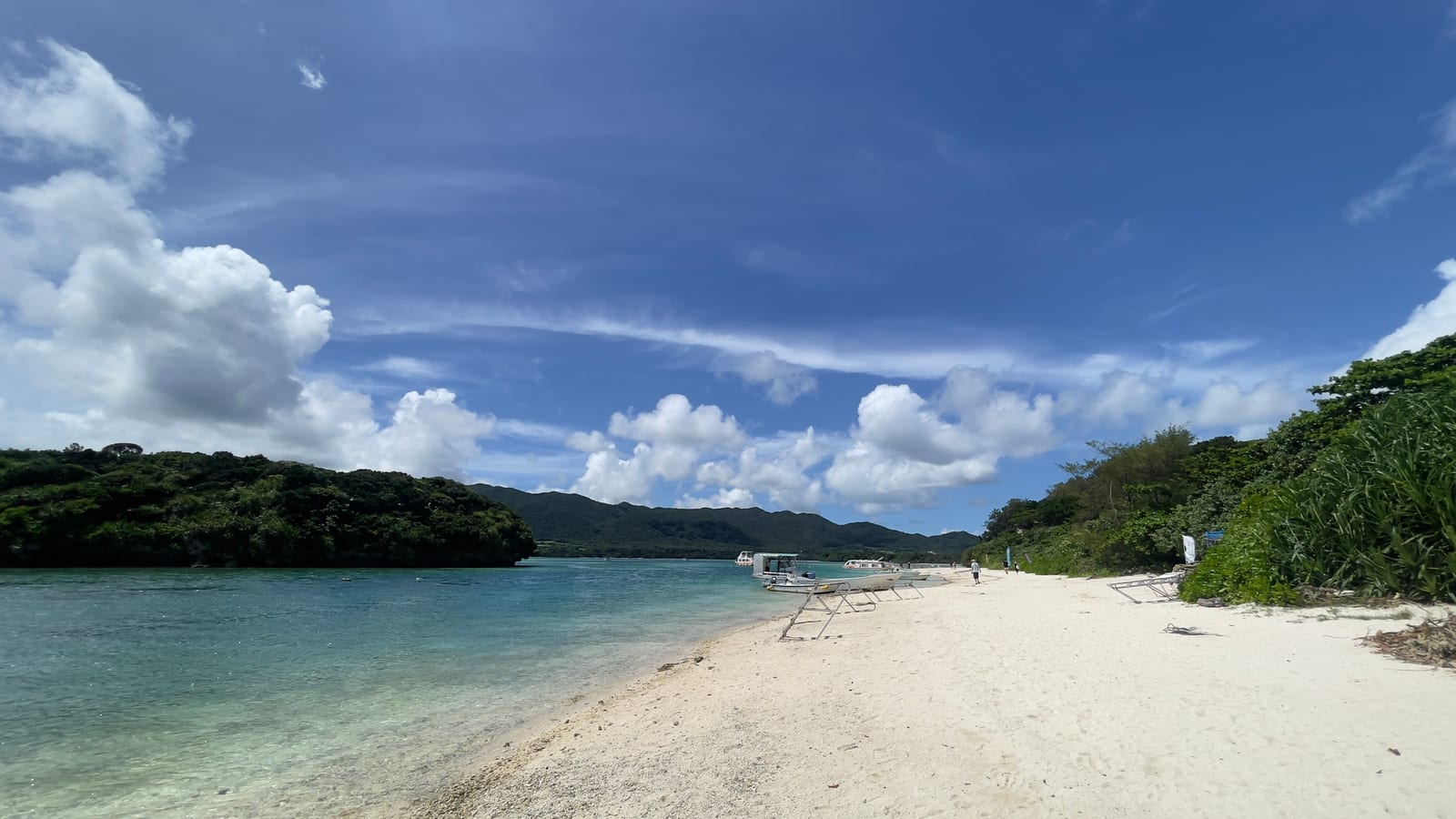 Kabira Bay with clear blue water, forested islands, boats, and a sandy shoreline.