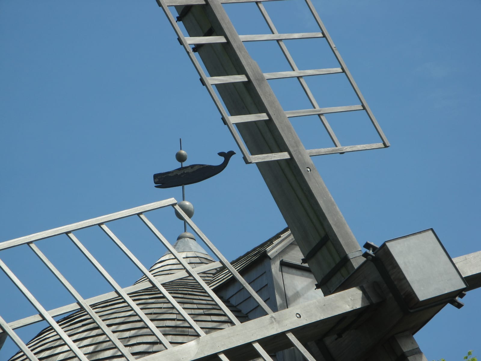 Beebe Windmill's wooden sails and whale-shaped weather vane against a clear blue sky.