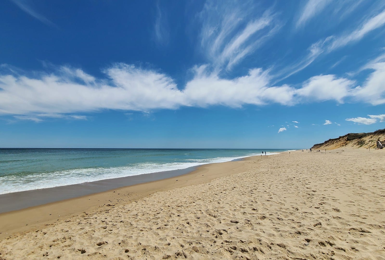The wide empty beach and bluff at Marconi Beach under a blue sky with wispy clouds.