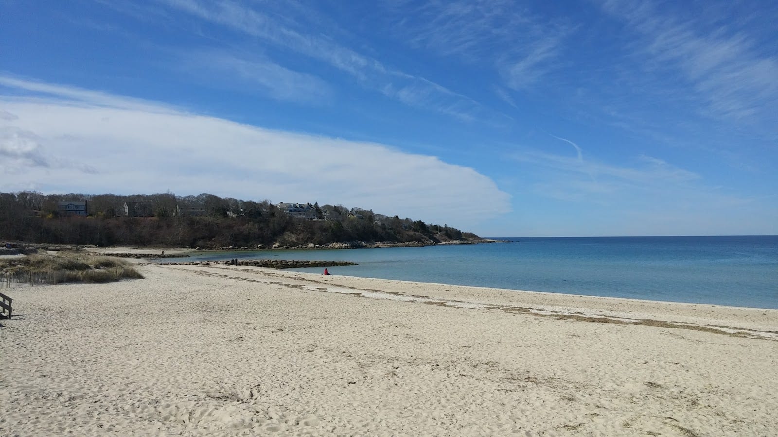 The curve of sand and a wooded point across the calm bay at Old Silver Beach.