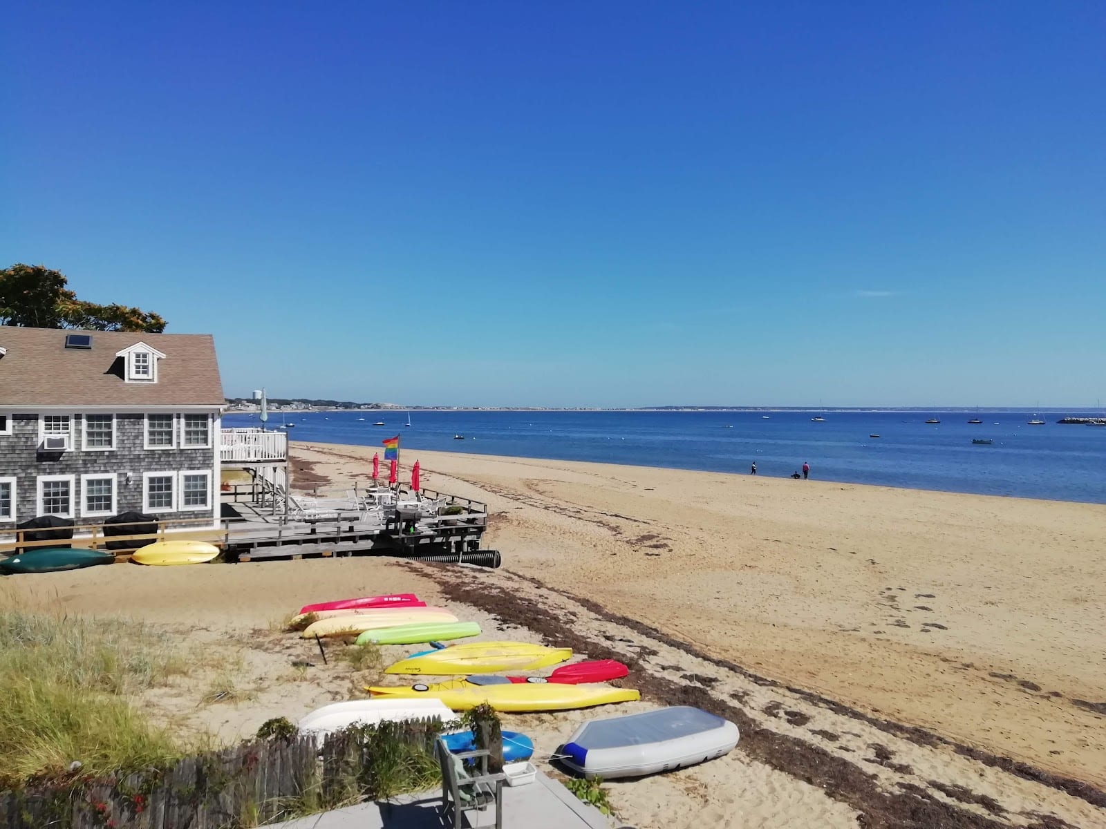 Colorful kayaks and paddleboards beside a boat-rental building at Skaket Beach.