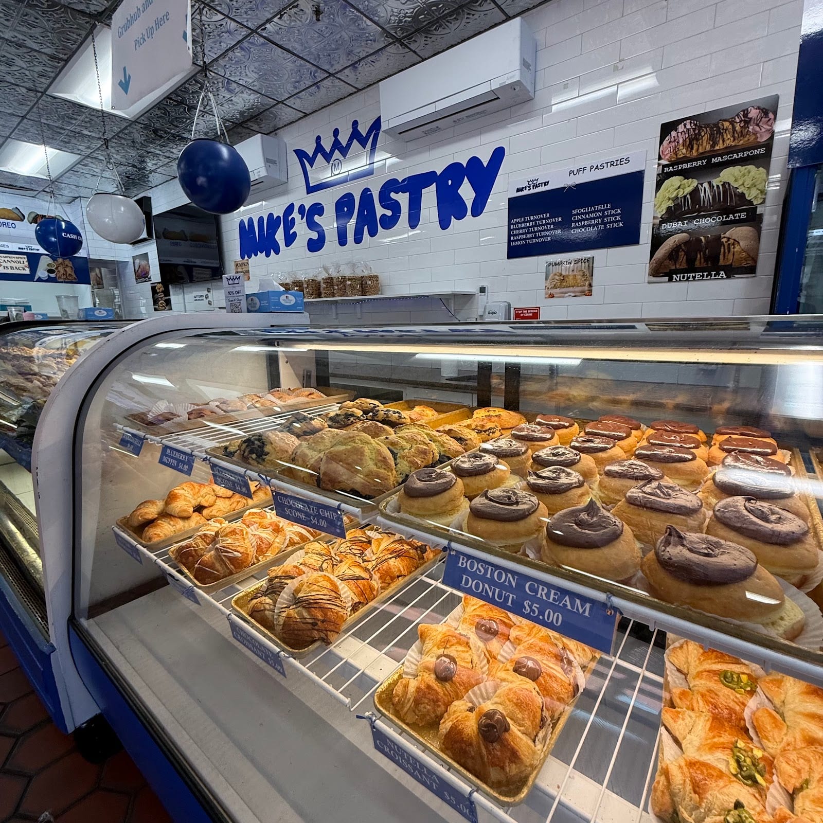 A bakery display case filled with rows of cannoli, pastries and Italian cookies.
