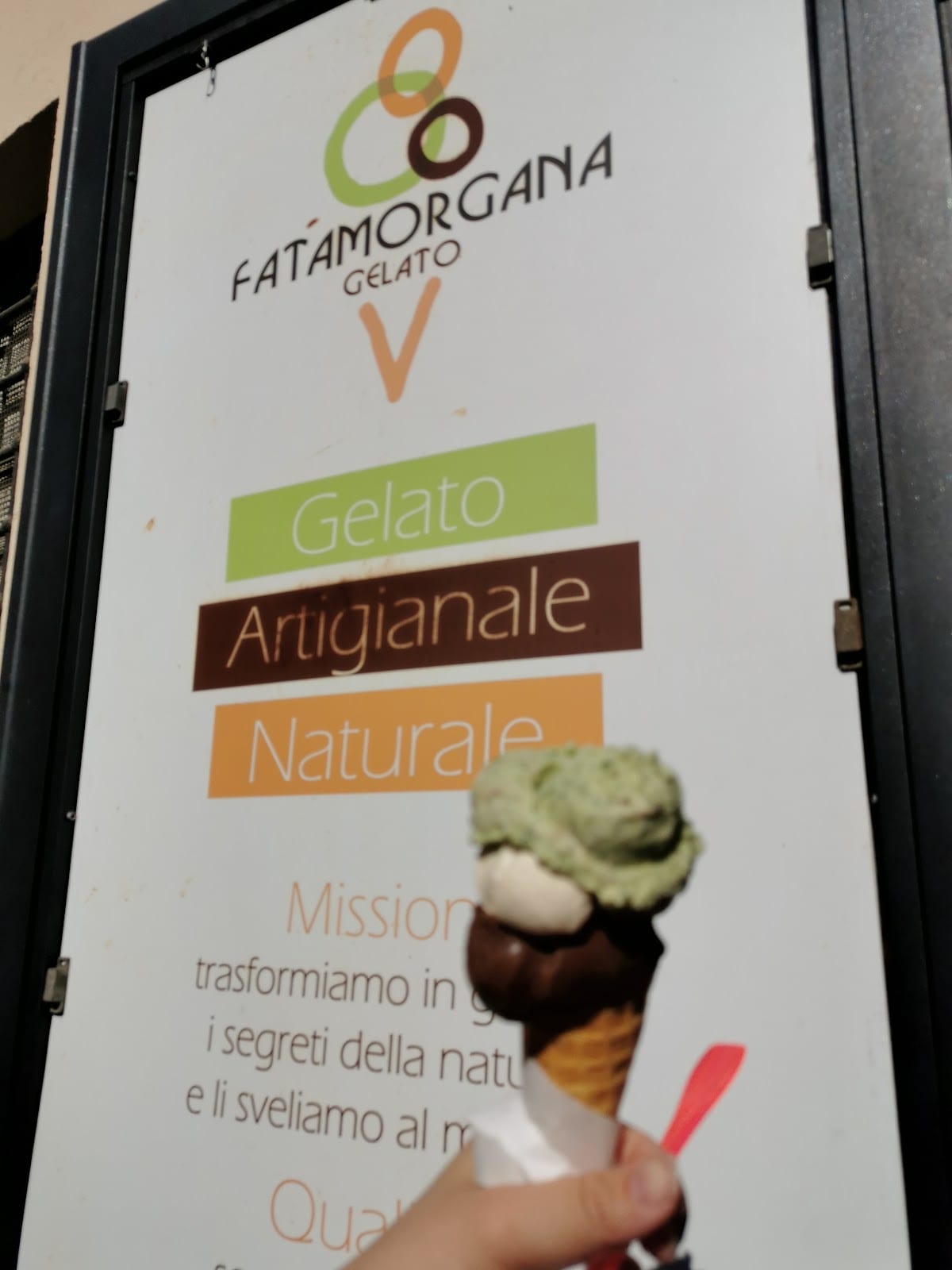 A Gelato Artigianale Naturale sign above a scoop of earthy-green pistachio at Fatamorgana.