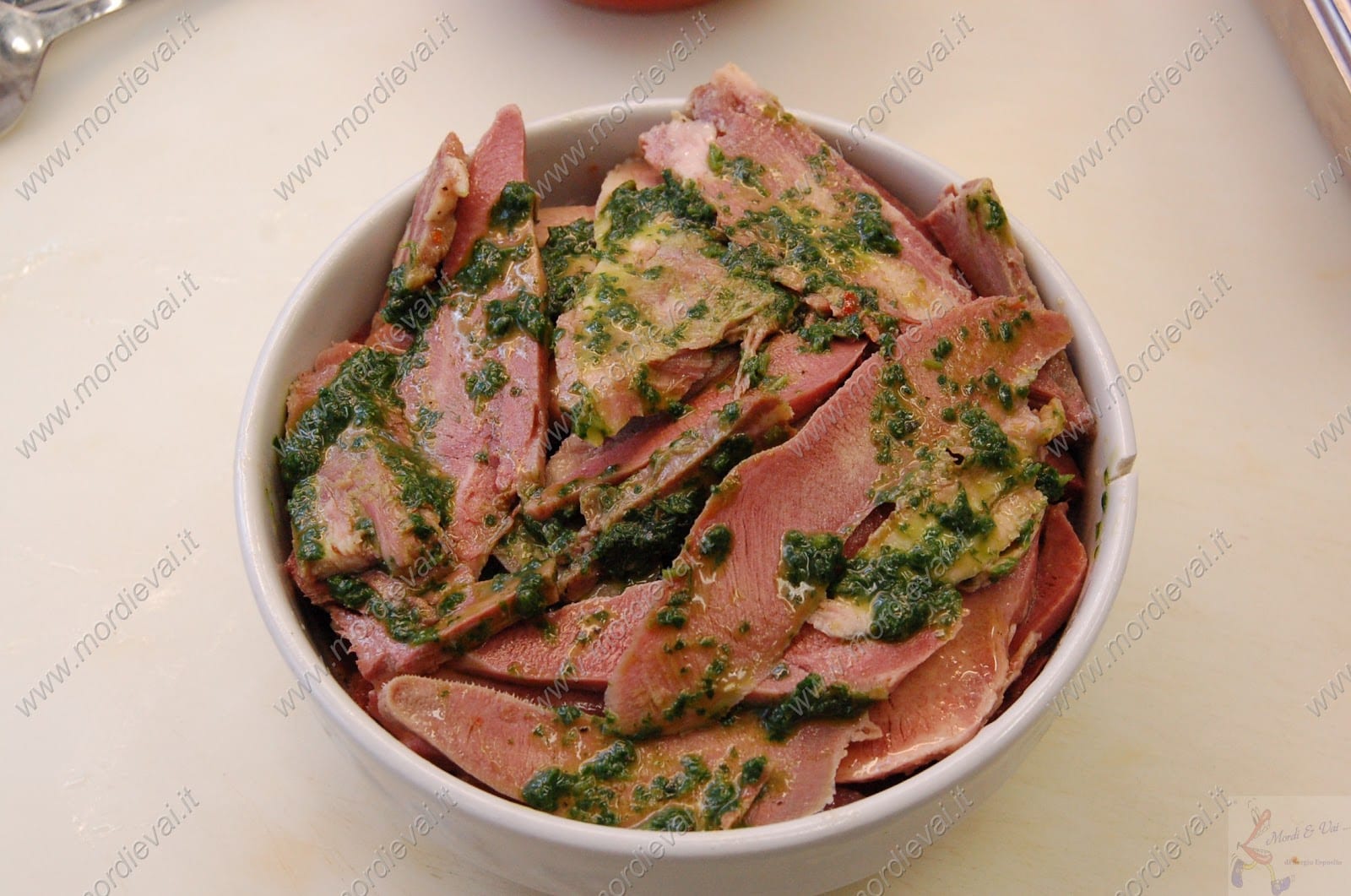 A bowl of sliced tongue in green salsa verde, a quinto quarto dish from Testaccio.