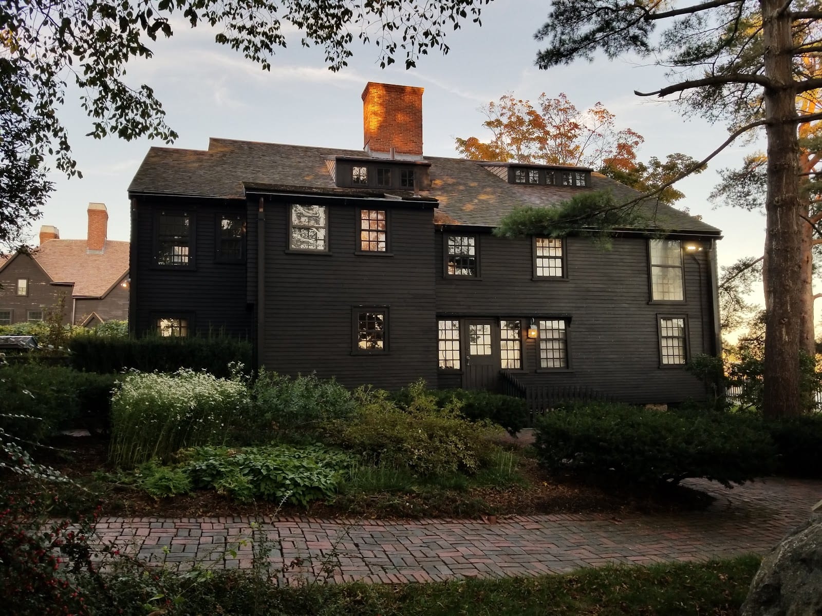 A historic wooden colonial building in Salem, Massachusetts with autumn trees.