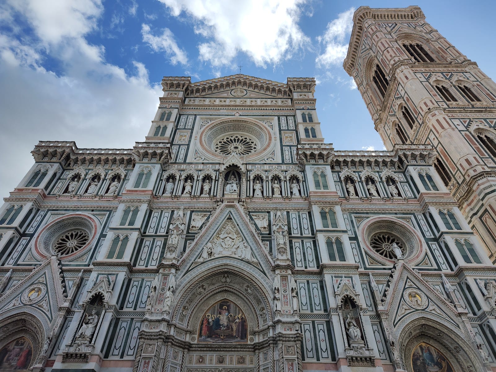 The ornate marble facade of Florence Cathedral in green, white and pink stone.