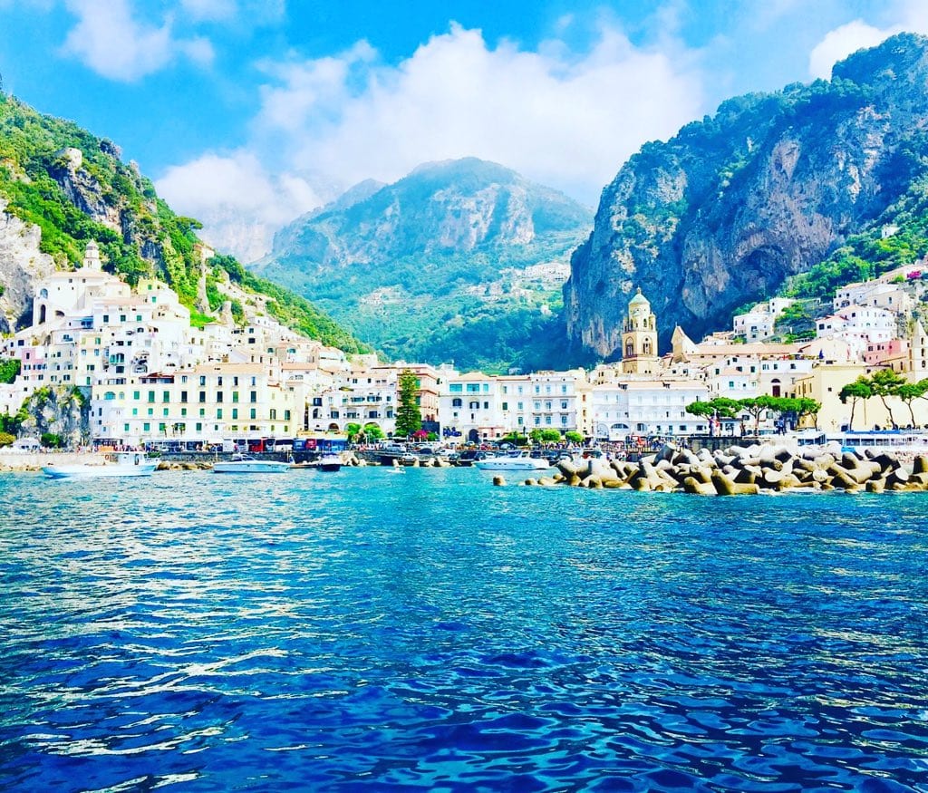 Amalfi's harbour and cliffs above the bright blue sea.
